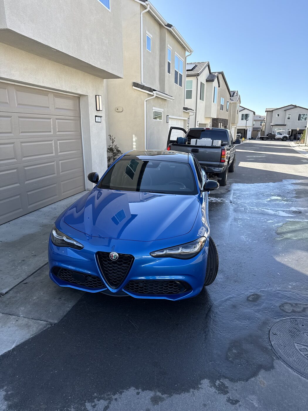 Freshly detailed blue Alfa Romeo sedan gleaming on an Orange County driveway